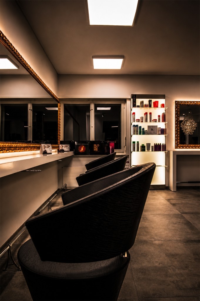 Styling-Arbeitsplätze mit grossen Spiegeln in Goldrahmen und schwarzen Stühlen