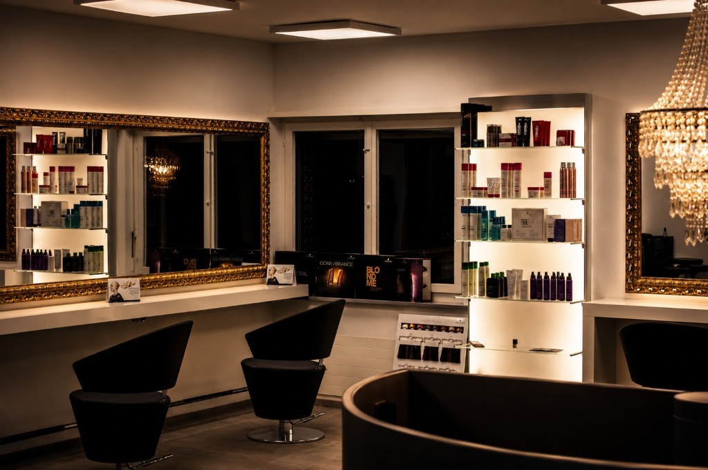 Styling-Zone mit Spiegeln, Stühlen und beleuchtetem Produktregal
